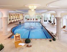 Innenpool mit Liegen, Säulen und großen Fenstern im Hotel Der Lärchenhof