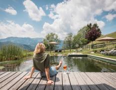 Eine Dame sitzt am Schwimmteich des Naturhotels Landhof Irschen