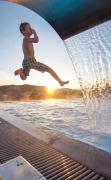 Ein Junge springt in den Aussenpool des AIGO Familien und Sport Resorts